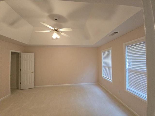 carpeted empty room with ceiling fan and a tray ceiling