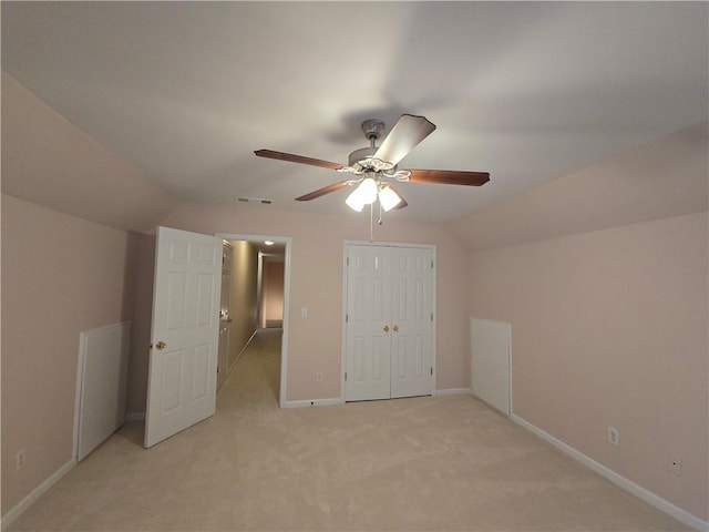 unfurnished bedroom featuring lofted ceiling, light carpet, ceiling fan, and a closet