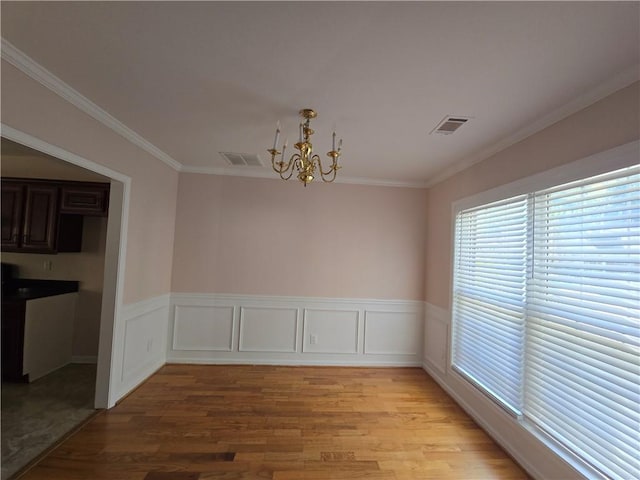 unfurnished dining area with crown molding, a notable chandelier, and light wood-type flooring