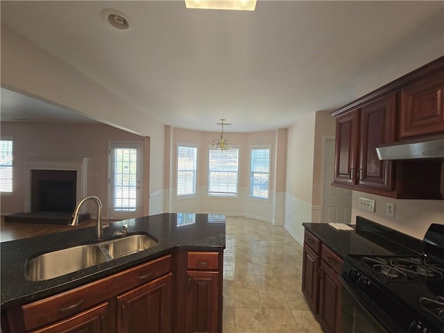 kitchen featuring sink, dark stone counters, black range with gas stovetop, pendant lighting, and a healthy amount of sunlight