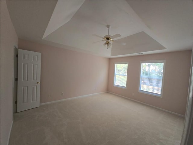 carpeted spare room featuring ceiling fan and a tray ceiling