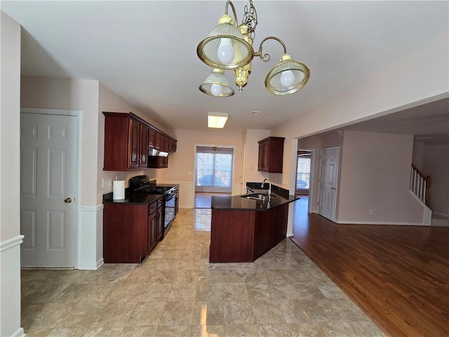 kitchen featuring black range with gas cooktop, sink, light hardwood / wood-style flooring, and an inviting chandelier