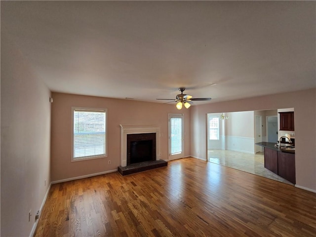 unfurnished living room with sink, ceiling fan, and light hardwood / wood-style flooring