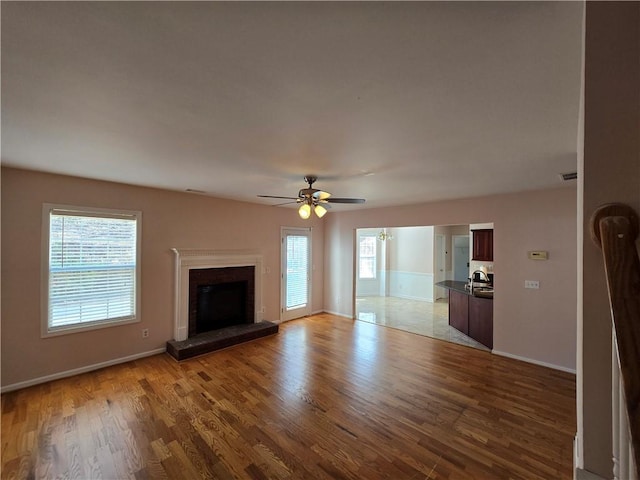 unfurnished living room featuring sink, ceiling fan, and light hardwood / wood-style flooring