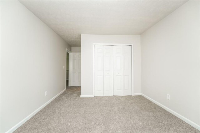 unfurnished bedroom with light carpet and a closet