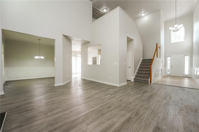 unfurnished living room featuring dark hardwood / wood-style floors, a chandelier, and high vaulted ceiling