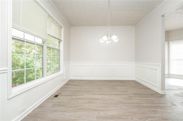 unfurnished dining area featuring ornamental molding, a notable chandelier, and light hardwood / wood-style floors