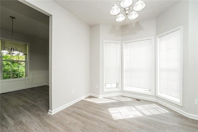 spare room with wood-type flooring and an inviting chandelier