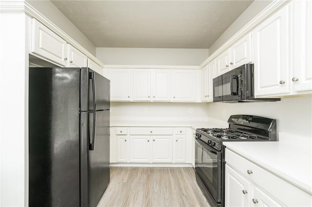 kitchen with light wood-type flooring, black appliances, a textured ceiling, and white cabinetry