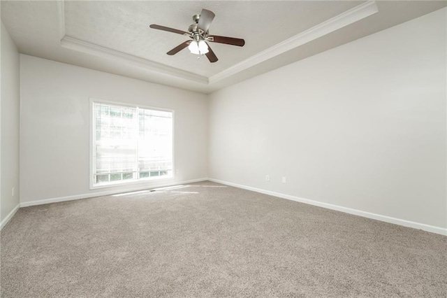 carpeted empty room with a raised ceiling, crown molding, and ceiling fan