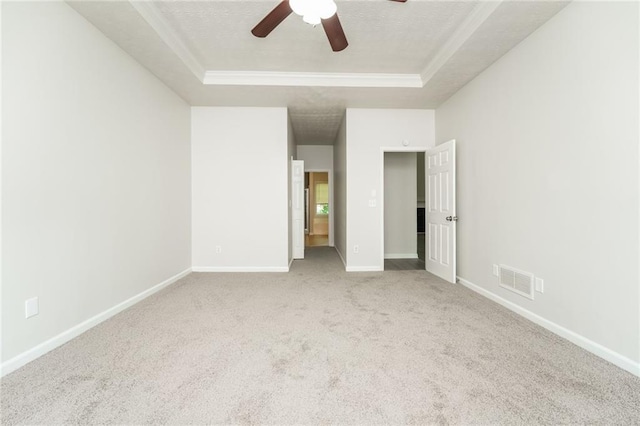 unfurnished bedroom featuring light carpet, a textured ceiling, a tray ceiling, and ceiling fan