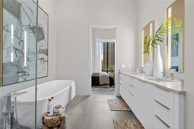 bathroom with vanity, a bathtub, tile patterned floors, and tile walls