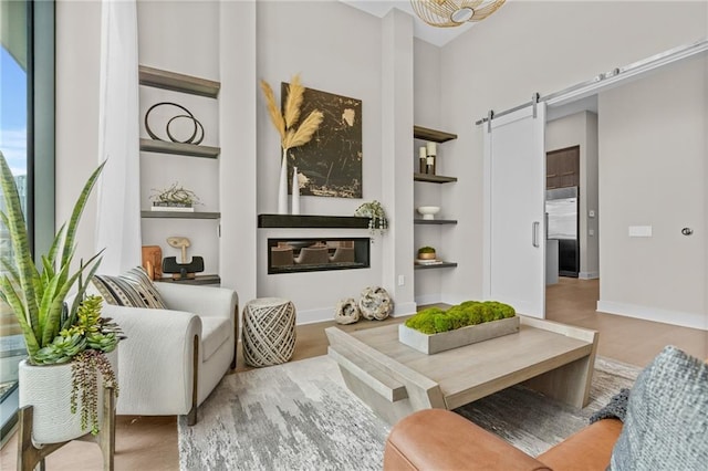 sitting room featuring a barn door, light hardwood / wood-style flooring, and built in shelves