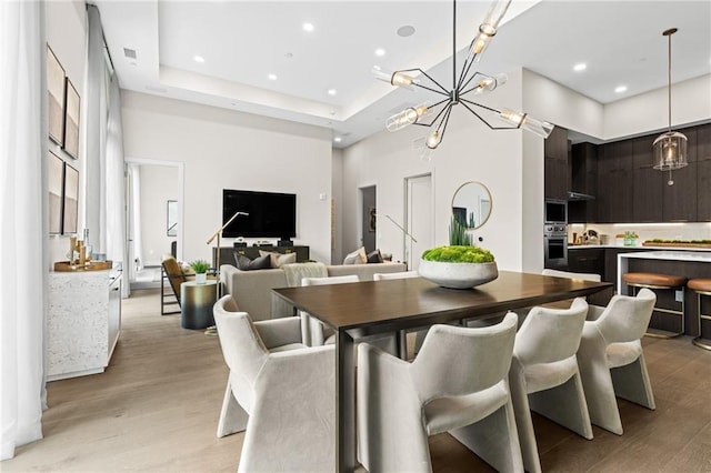 dining room with light hardwood / wood-style floors, a chandelier, and a high ceiling