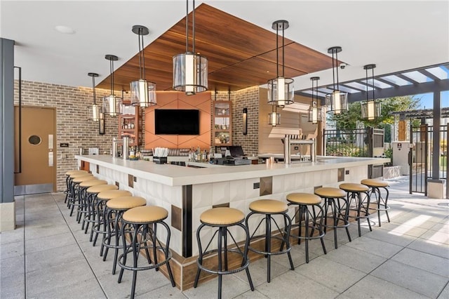 kitchen featuring decorative light fixtures, a breakfast bar area, and brick wall