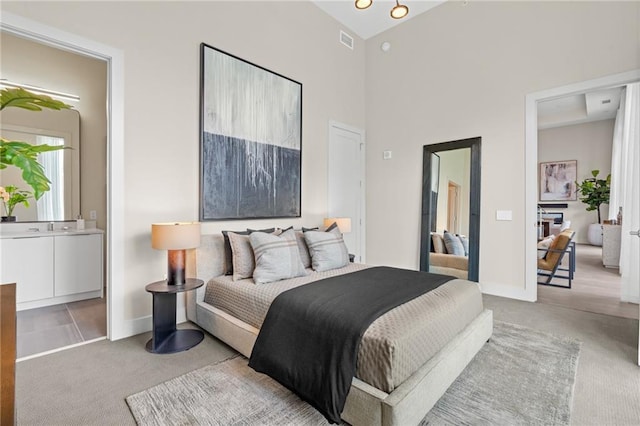 bedroom featuring ensuite bath and high vaulted ceiling