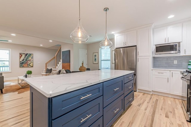 kitchen with light wood finished floors, tasteful backsplash, a kitchen island, appliances with stainless steel finishes, and white cabinetry