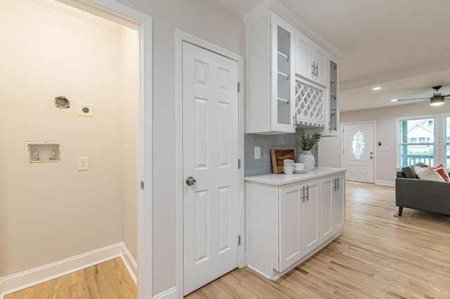 kitchen featuring light wood-type flooring, light countertops, baseboards, and white cabinetry