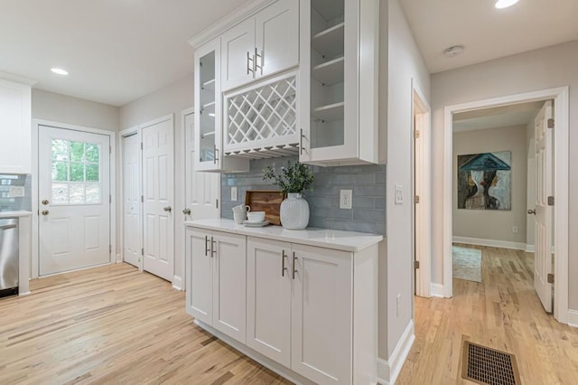 kitchen with light countertops, visible vents, backsplash, white cabinetry, and light wood-type flooring