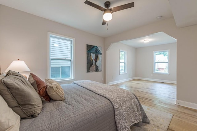 bedroom with light wood finished floors, a ceiling fan, and baseboards