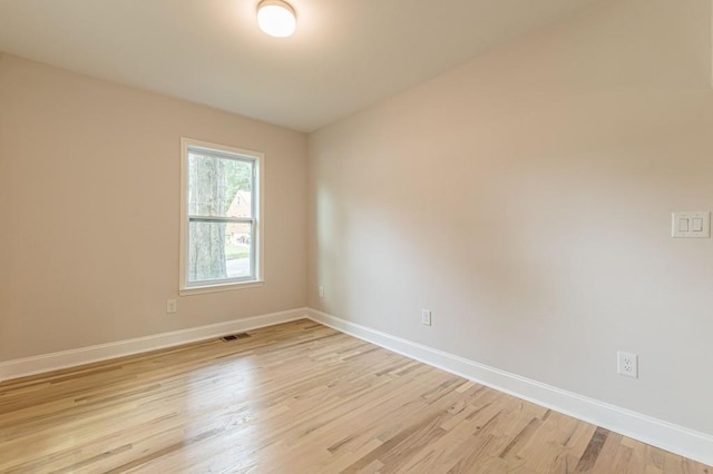 empty room featuring light wood-style floors, baseboards, and visible vents