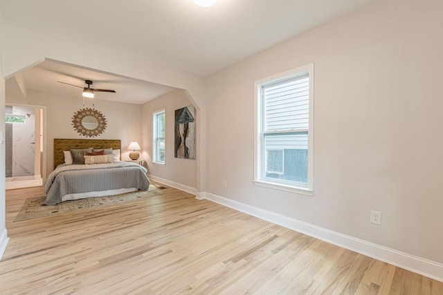 bedroom featuring arched walkways, wood finished floors, a ceiling fan, and baseboards