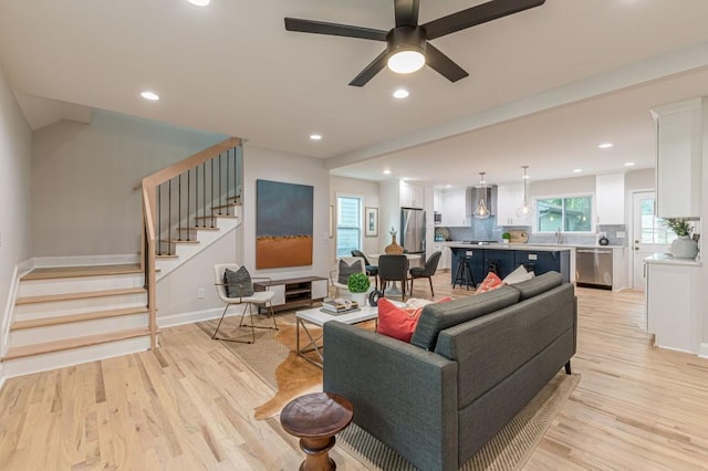 living area with a ceiling fan, recessed lighting, stairway, and light wood finished floors