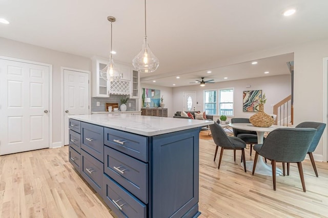 kitchen featuring a center island, decorative light fixtures, recessed lighting, light wood-style floors, and white cabinetry