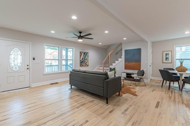 living room featuring recessed lighting, stairway, light wood-type flooring, and a healthy amount of sunlight