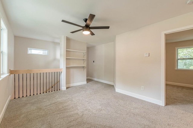 carpeted spare room with ceiling fan and baseboards