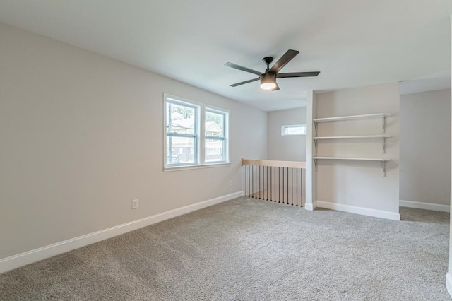 carpeted spare room with a ceiling fan and baseboards