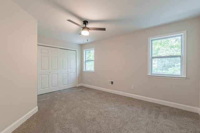 unfurnished bedroom with a closet, carpet, visible vents, and baseboards