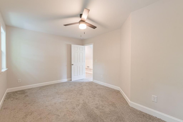 carpeted spare room featuring baseboards and a ceiling fan