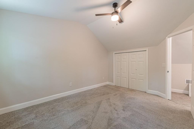 unfurnished bedroom featuring lofted ceiling, carpet floors, a closet, and baseboards