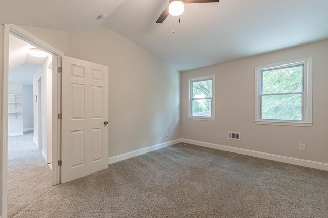 carpeted empty room with a ceiling fan, visible vents, vaulted ceiling, and baseboards