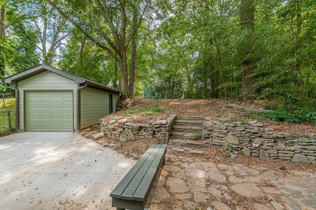 view of yard with concrete driveway, an outdoor structure, and a detached garage