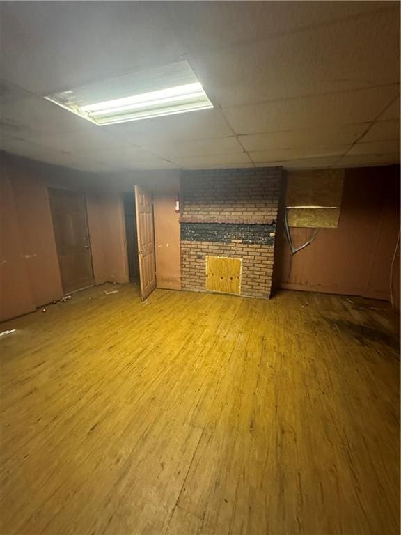 basement with a drop ceiling, brick wall, and hardwood / wood-style floors