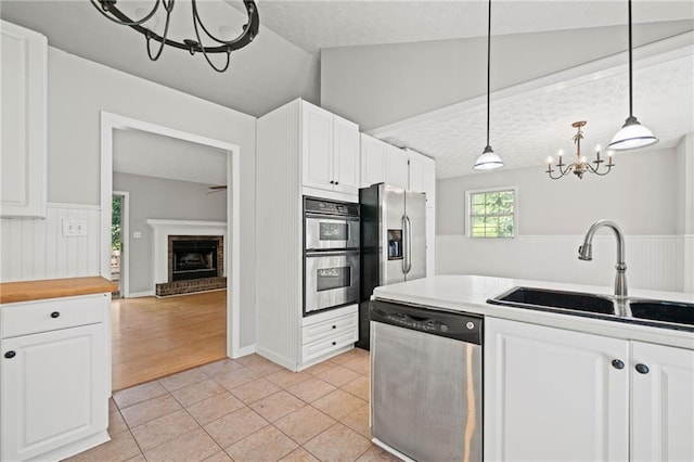94 Park Ave W, Dallas, GA 30157 - kitchen featuring appliances with stainless steel finishes, a chandelier, white cabinetry, light tile patterned floors, and hanging light fixtures