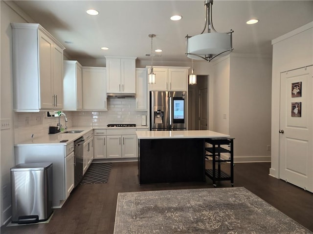 kitchen with a kitchen island, a sink, stainless steel fridge, under cabinet range hood, and dishwashing machine