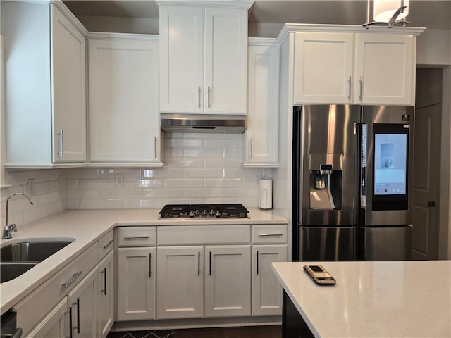 kitchen with stainless steel appliances, light countertops, a sink, and under cabinet range hood