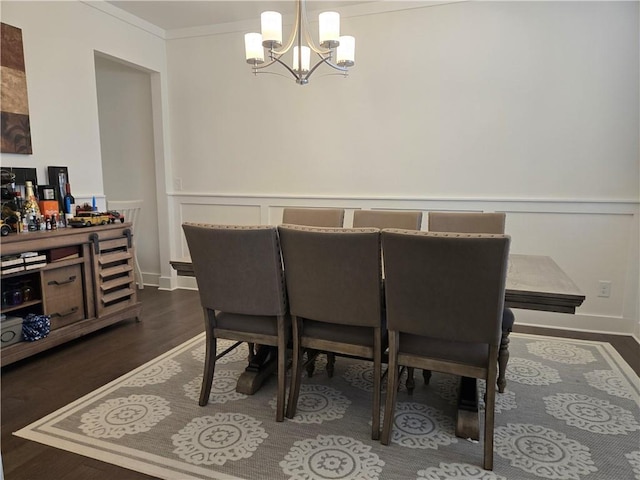 dining room with a notable chandelier, dark wood finished floors, and ornamental molding