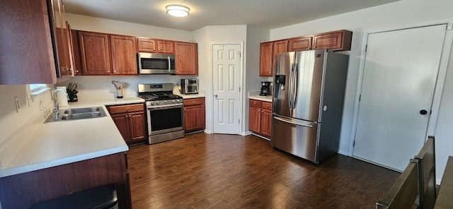 kitchen with appliances with stainless steel finishes, sink, and dark wood-type flooring