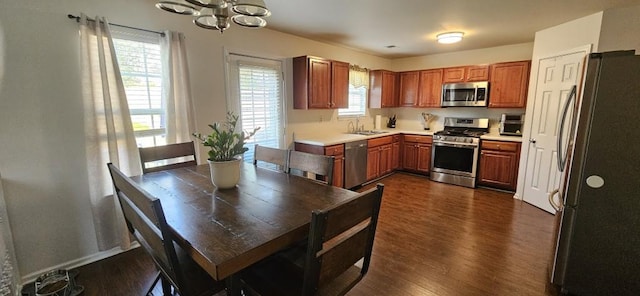 kitchen with sink, dark wood-type flooring, stainless steel appliances, and a notable chandelier