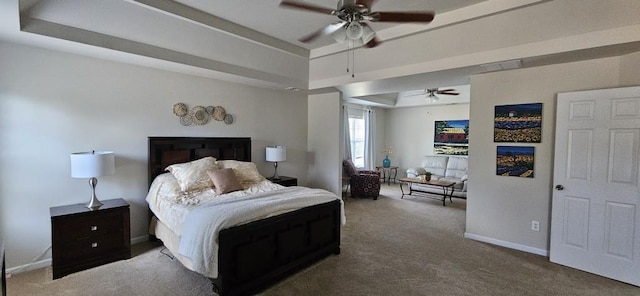 carpeted bedroom with ceiling fan and a raised ceiling