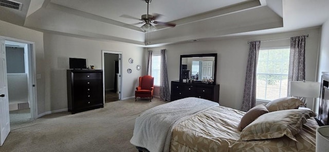 carpeted bedroom featuring ceiling fan and a raised ceiling