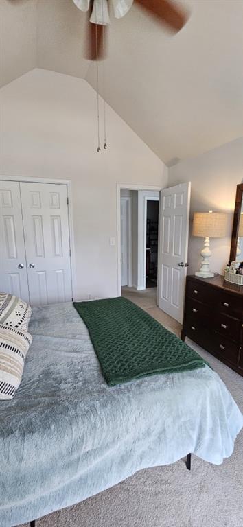 carpeted bedroom featuring ceiling fan, a closet, and vaulted ceiling