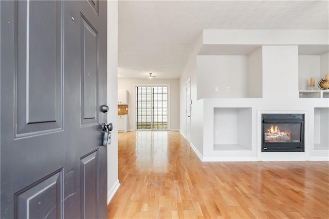 foyer entrance featuring a textured ceiling and light wood-type flooring