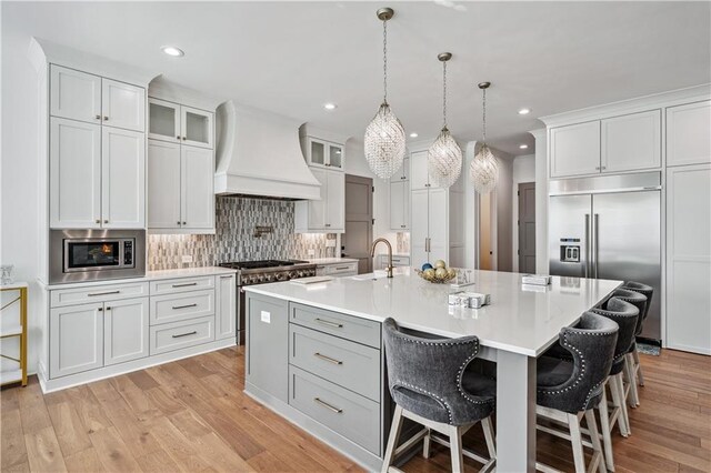 109 Owens Mill Pl, Canton, GA 30115 - kitchen featuring custom exhaust hood, wood finished floors, hanging light fixtures, stainless steel appliances, and light countertops