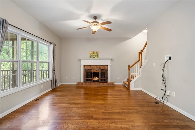 unfurnished living room featuring ceiling fan, a fireplace, and dark hardwood / wood-style flooring