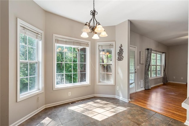 interior space with a notable chandelier, dark wood-type flooring, and a healthy amount of sunlight